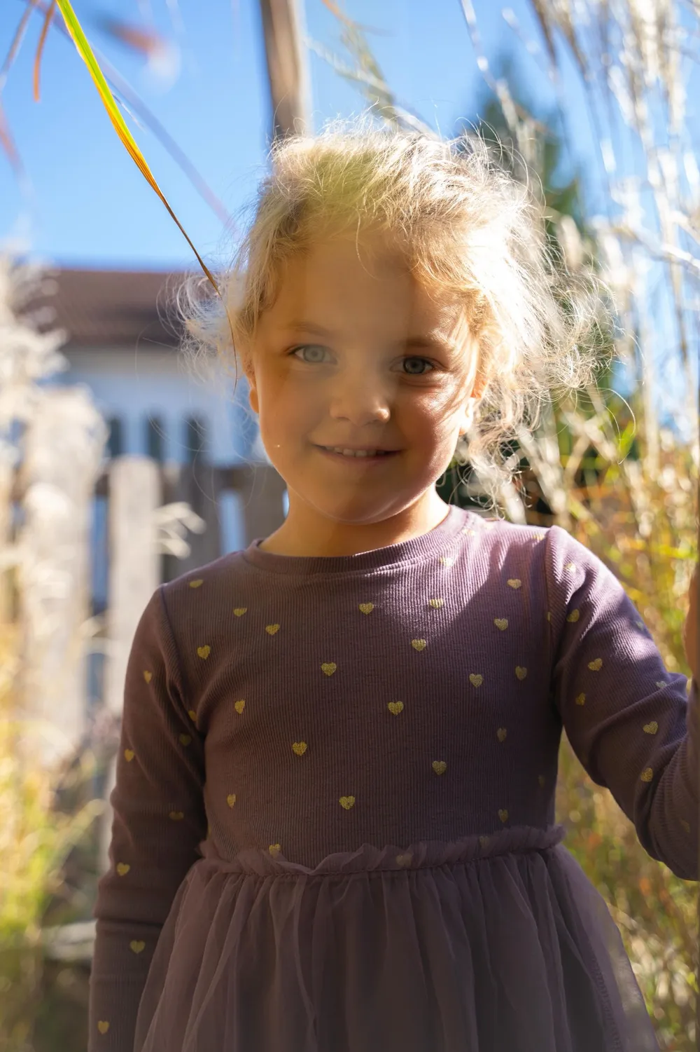 Mädchen im Herbstlicht vor hohem Gras