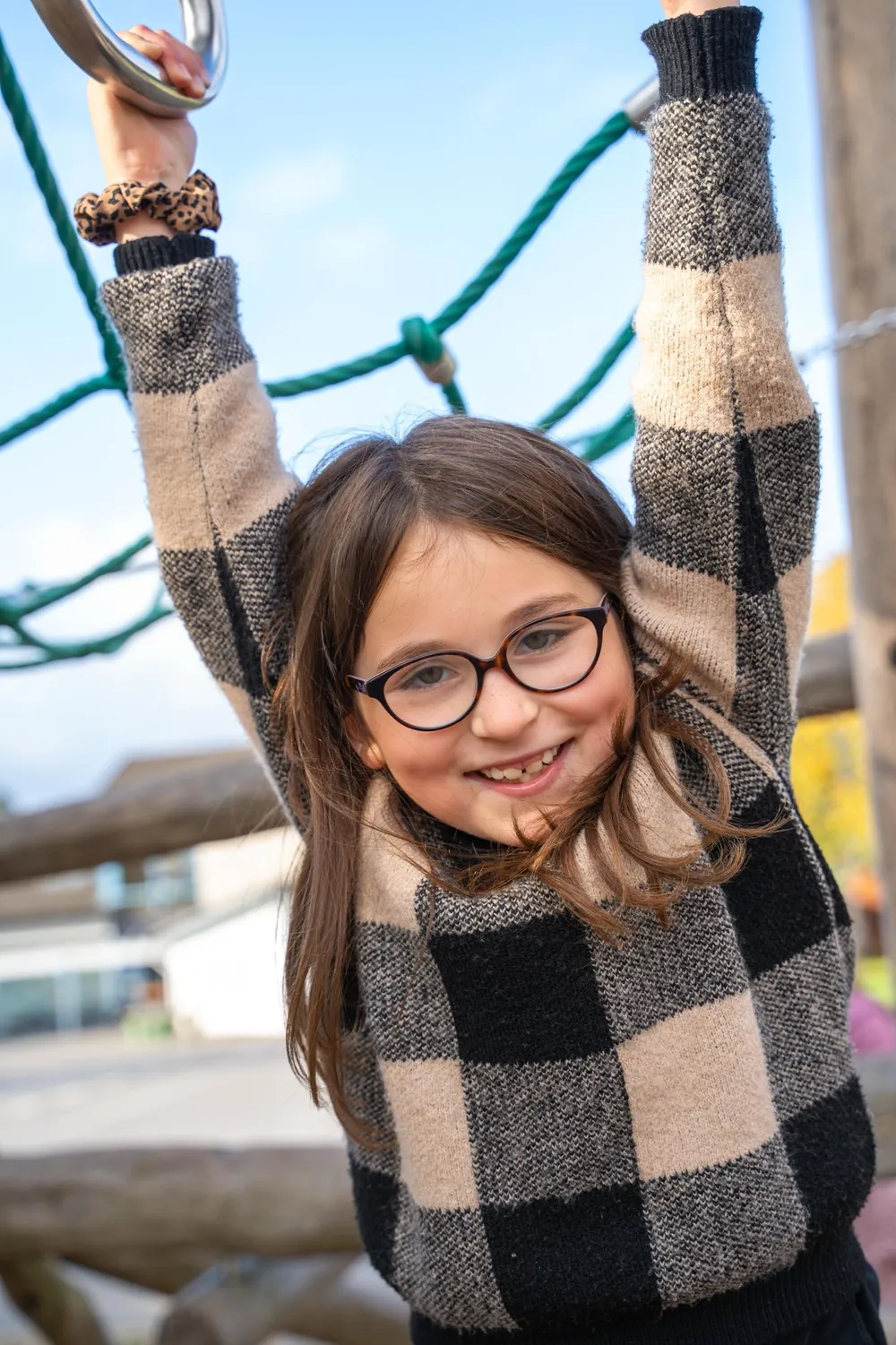 Mädchen mit Brille hängt am Klettergerüst