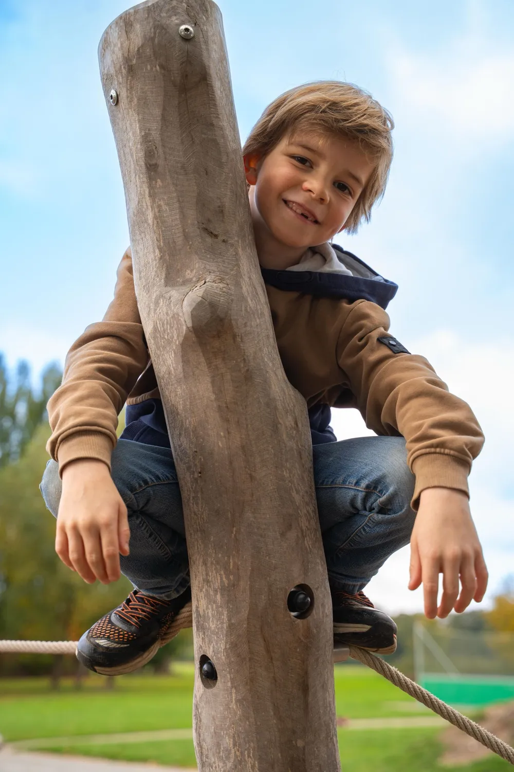 Junge klettert an einem Holzstamm