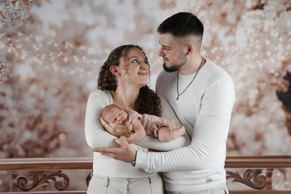 Junge Eltern halten ihr neugeborenes Baby im Studio und schauen sich verliebt an